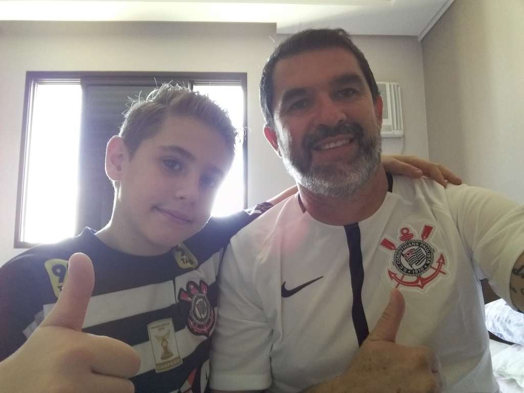 Ao lado do seu filho João Pedro, Edenilson Lacotis parece estar feliz com a sua nova camisa do Corinthians